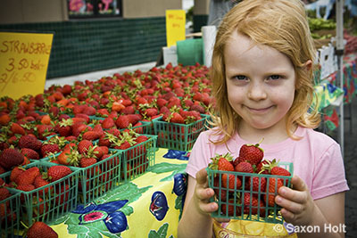 child with strawberries at farmer's market