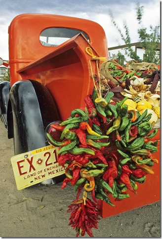 A red pickup truck adorned with a chile ristra and loaded with bounty from the autumn harvest create a colorful scene at a fruit stand near the small village of Velarde in northern New Mexico.
